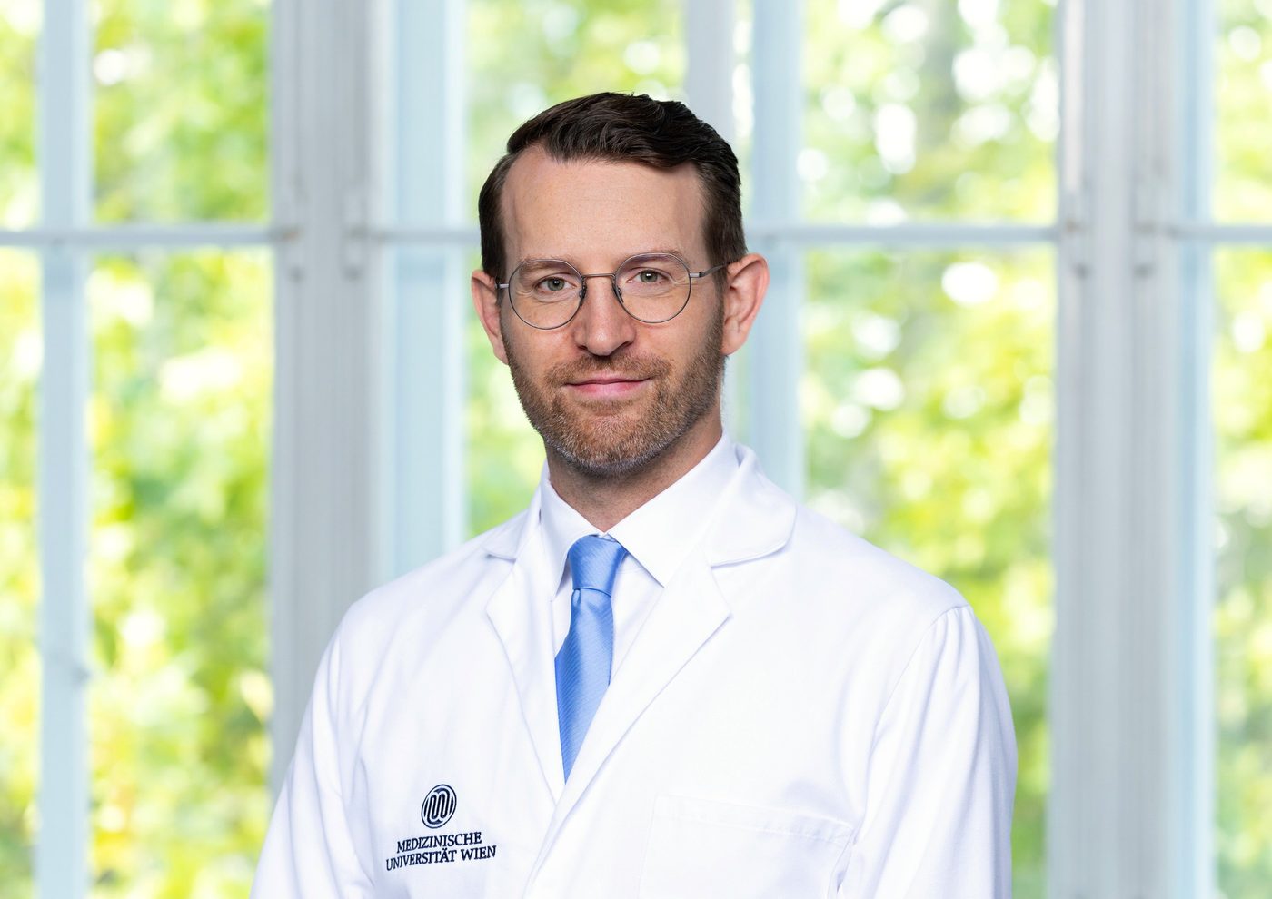 Dr. Julian Veser im Arztkittel der Medizinischen Universität Wien